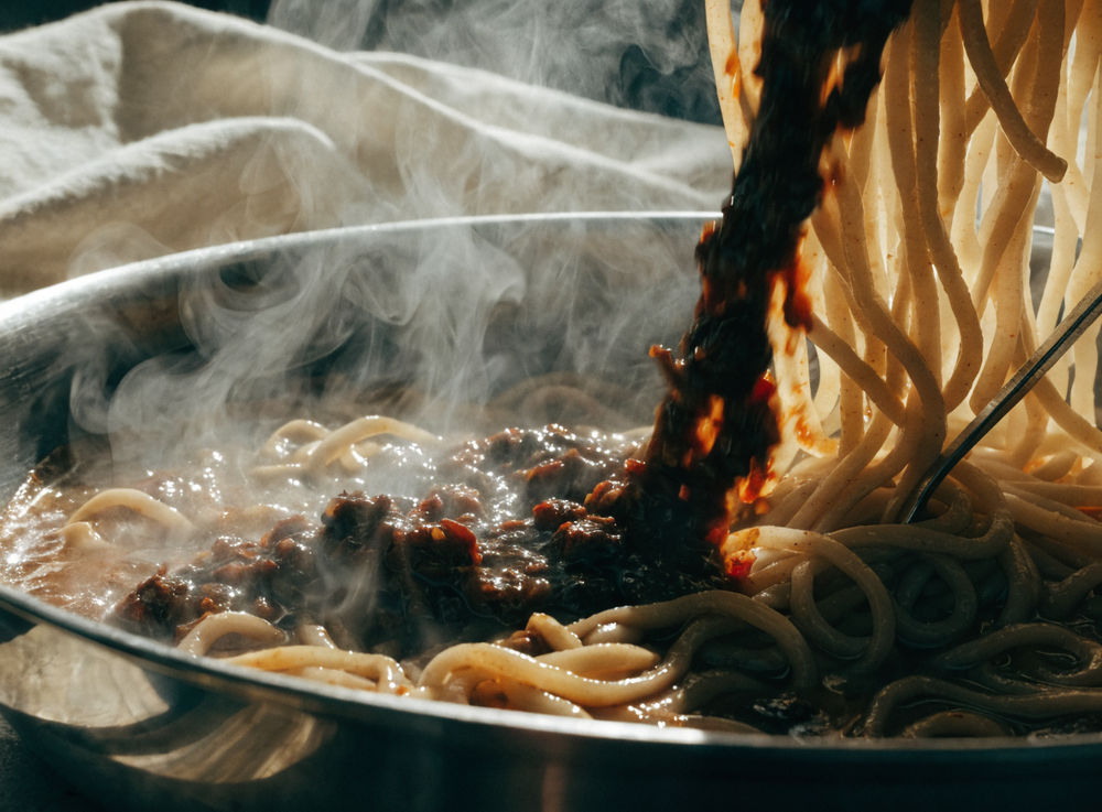 Chilipaste wird unter Nudeln gerührt
